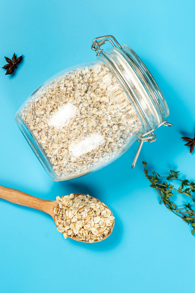 Банка с овсяными хлопьями и ложкой на голубом фоне