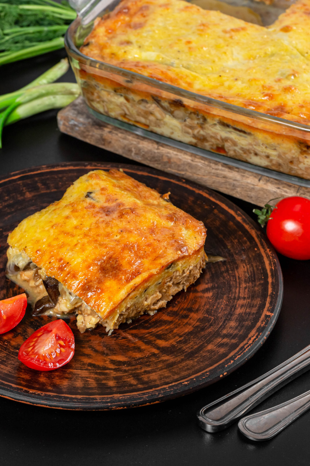 Лазанья на тарелке с помидорами и зеленью