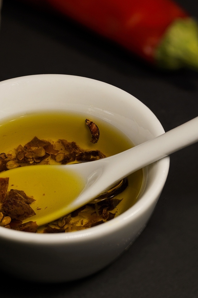 Оливковое масло в тарелке на столе с перцем и чесноком