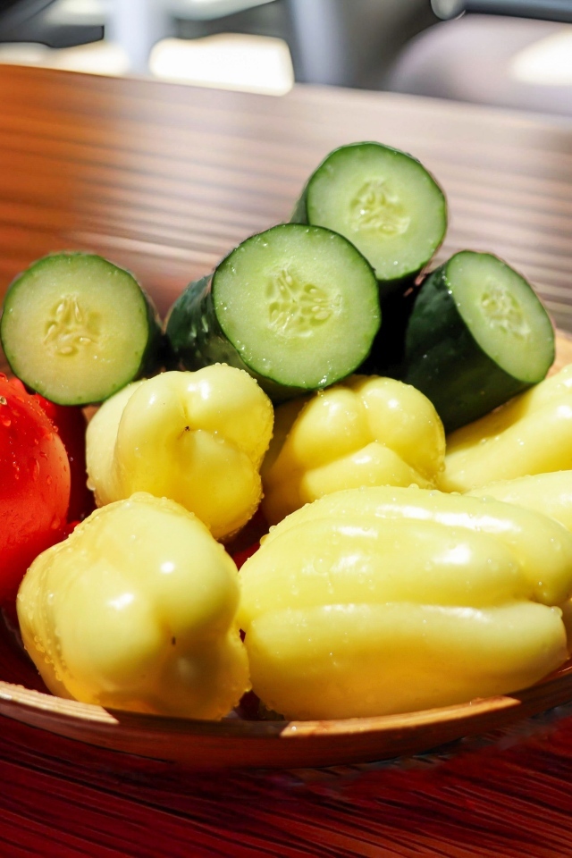 Перец, помидоры и зеленые огурцы на тарелке на столе