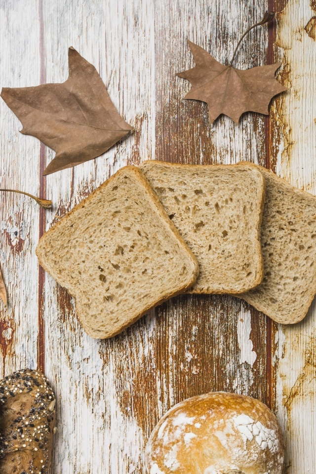 Куски хлеба с листьями на деревянном столе