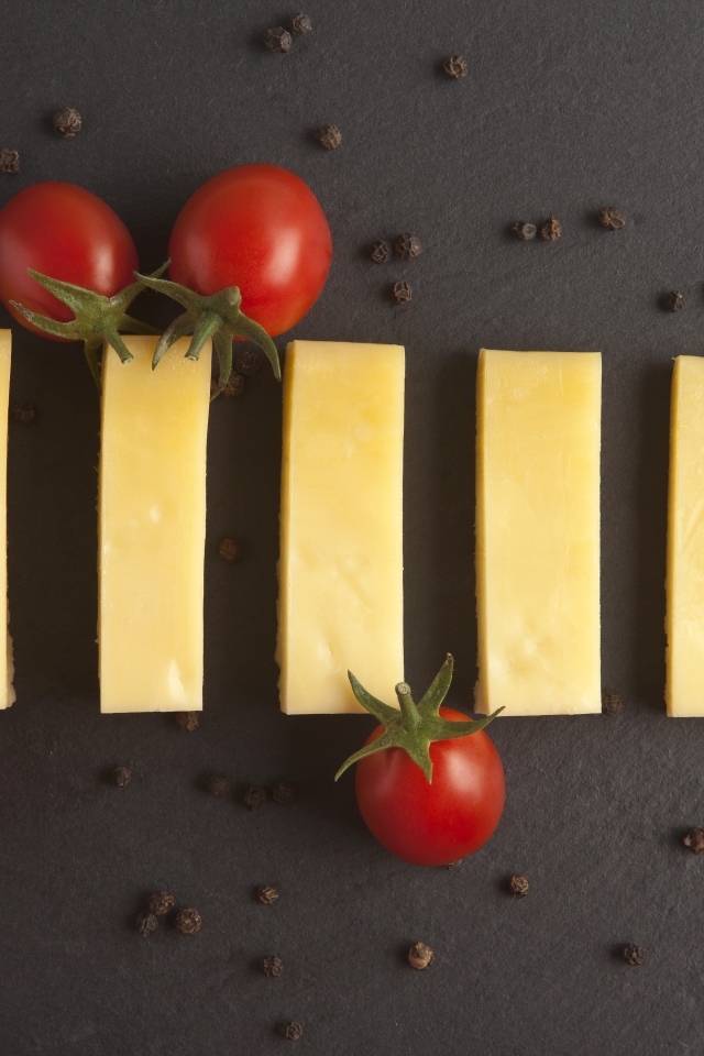 Кусочки сыра с помидорами на сером столе
