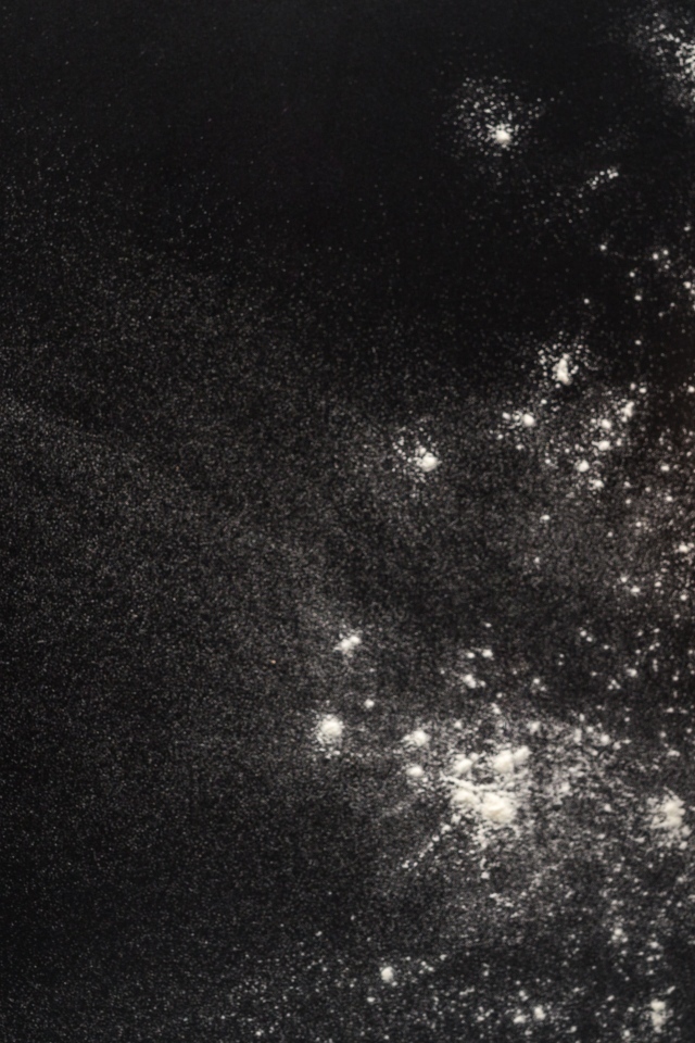 Сырое тесто на черном столе с мукой