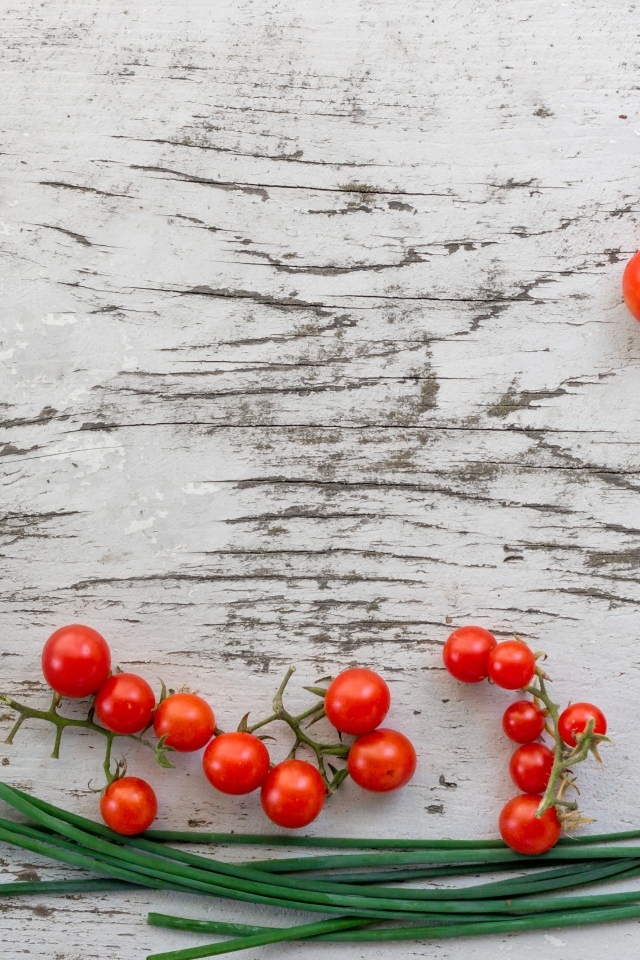 Красные помидоры с зеленым луком на деревянном столе