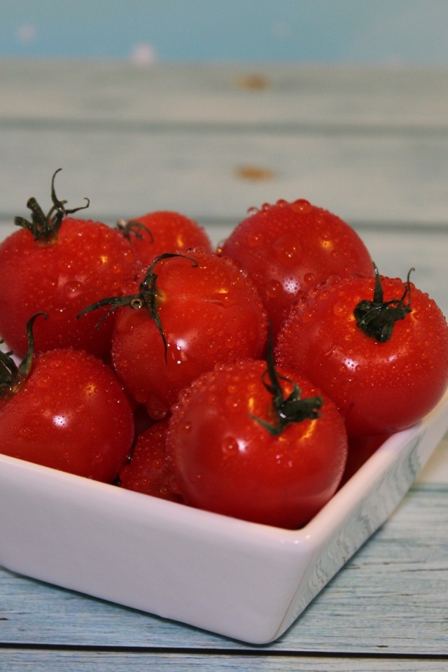 Красные мокрые помидоры в белой тарелке