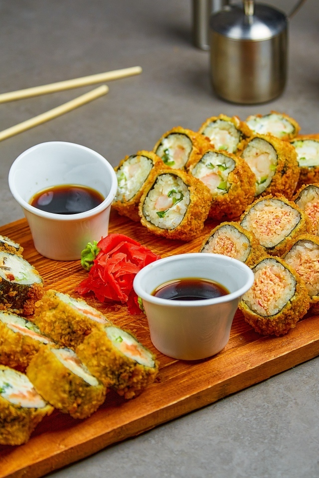 Роллы с соевым соусом на доске на столе