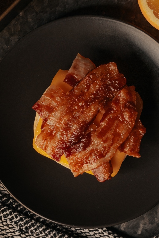 Бутерброд с сыром и жареным беконом на тарелке