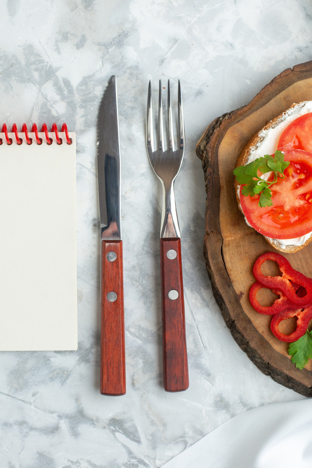 Бутерброды на столе со столовыми приборами и блокнотом