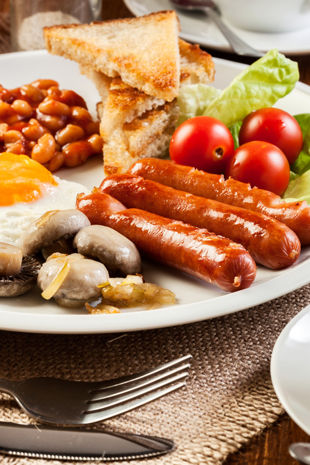 Яичница, сосиски и овощи на тарелке на завтрак