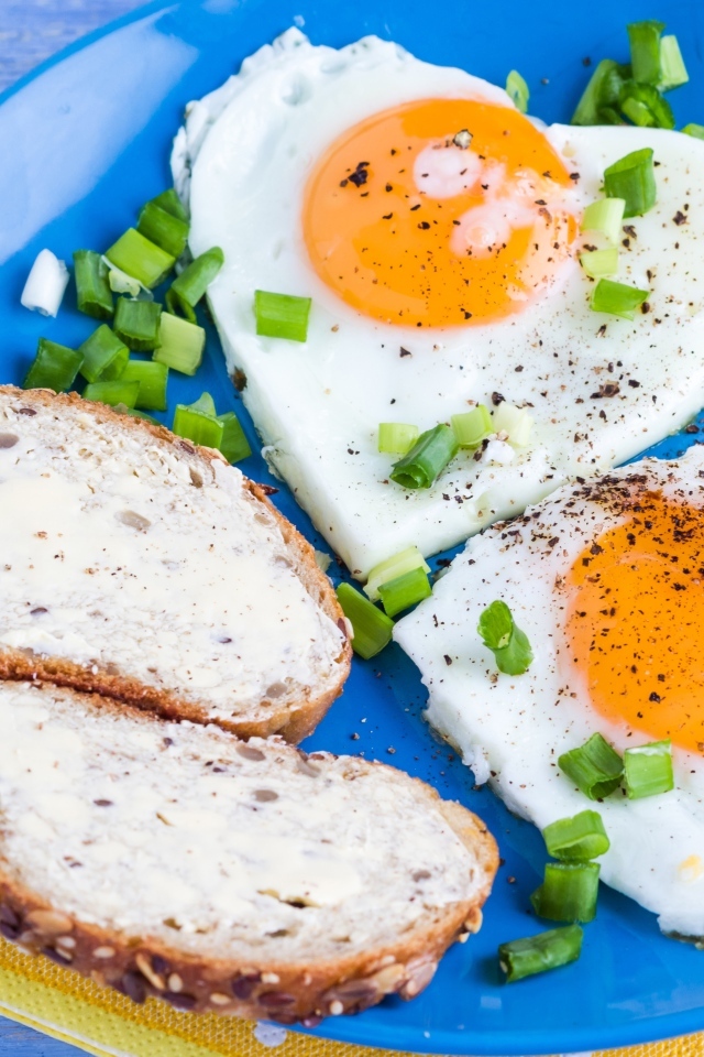 Яичница с бутербродами и зеленым луком на тарелке