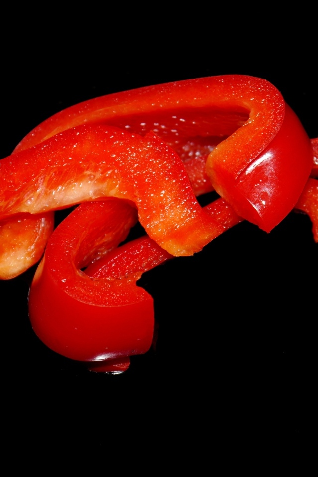 Нарезанный сладкий красный перец на черном фоне