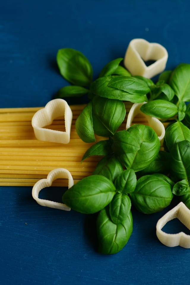 Спагетти на синем фоне с листьями базилика