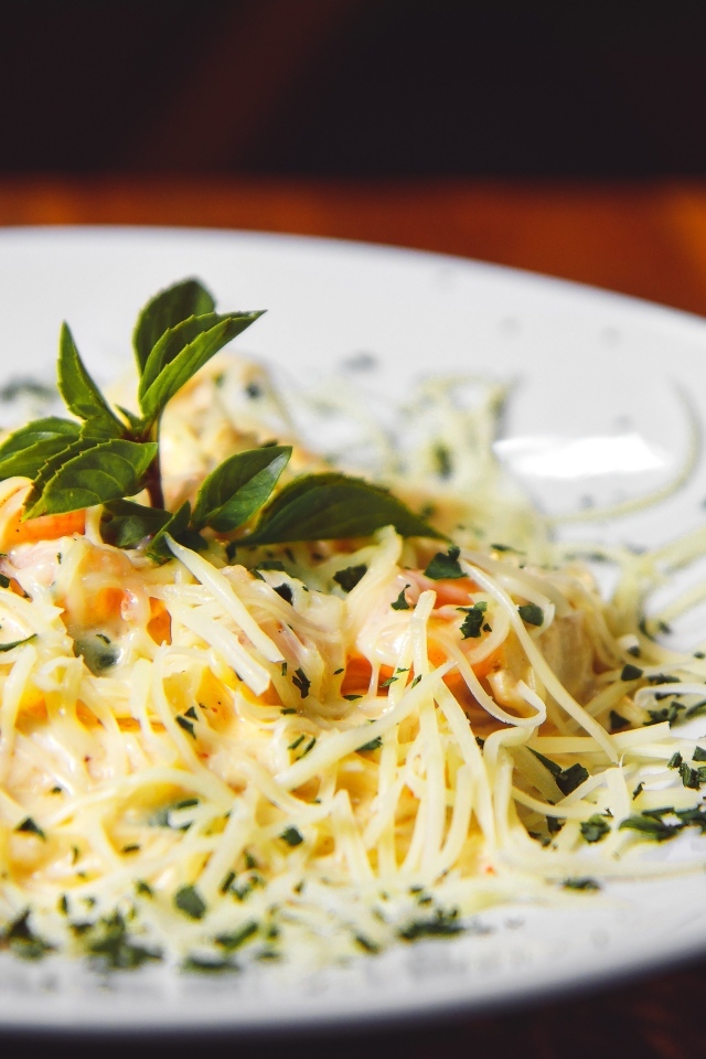 Спагетти с сыром и помидорами на белой тарелке