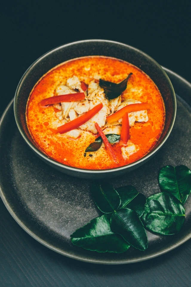 Острый суп в тарелке на черном фоне