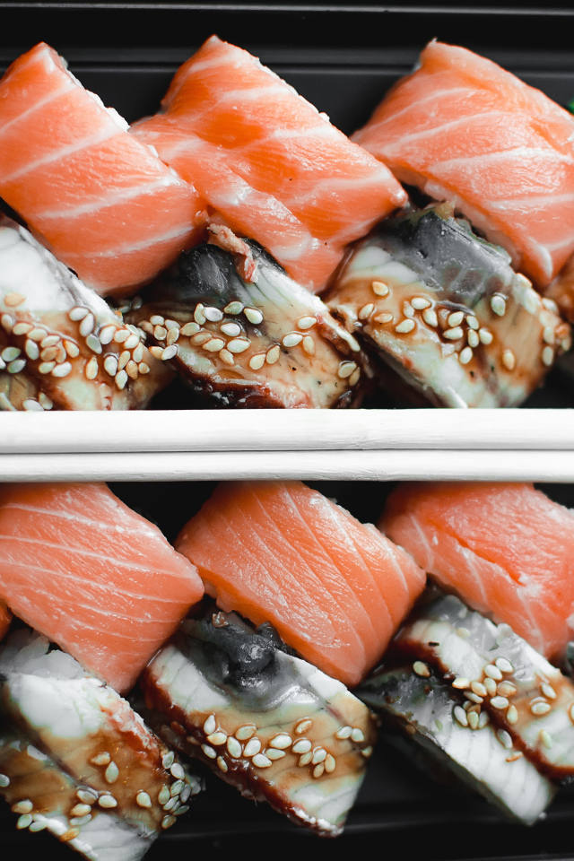 Суши с рыбой на черной тарелке с палочками