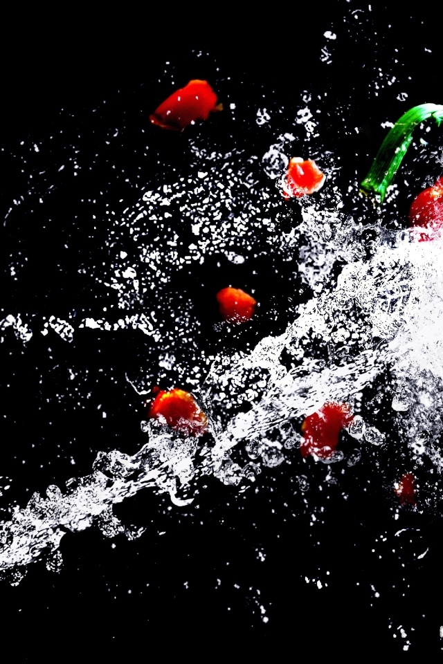 Сладкий красный перец в брызгах воды на черном фоне