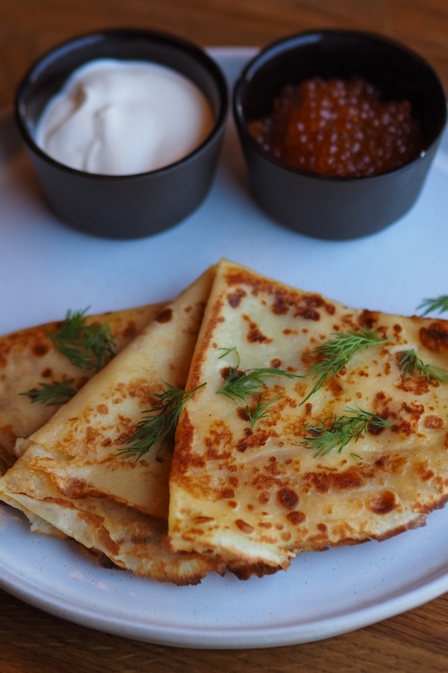 Тонкие блинчики на тарелке с красной икрой и сметаной