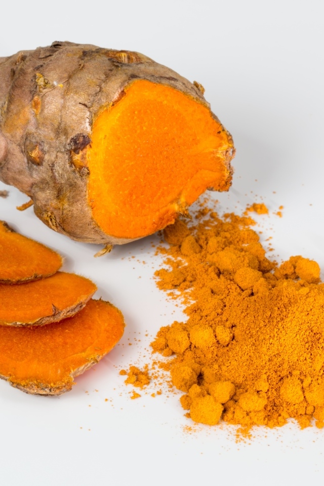 Корень куркумы с порошком на сером фоне