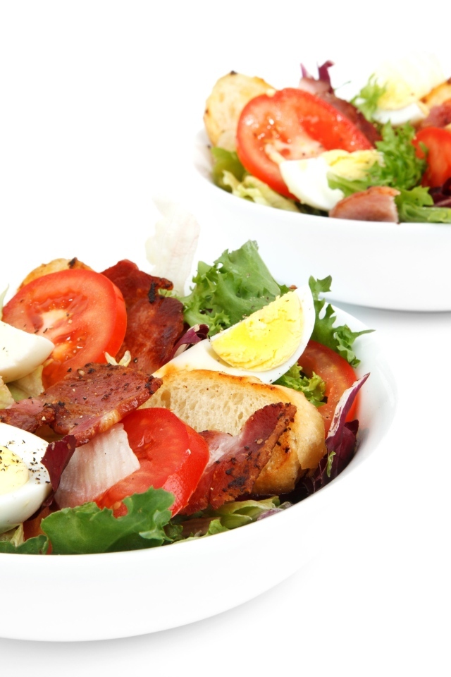 Две миски вкусного салата на белом фоне