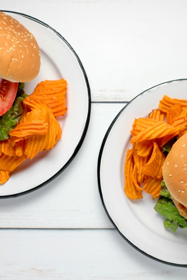 Два гамбургера на тарелке с чипсами