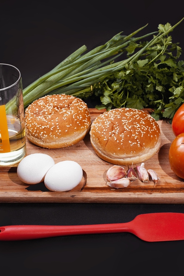 Овощи, яйца, зелень и булочки на черном фоне