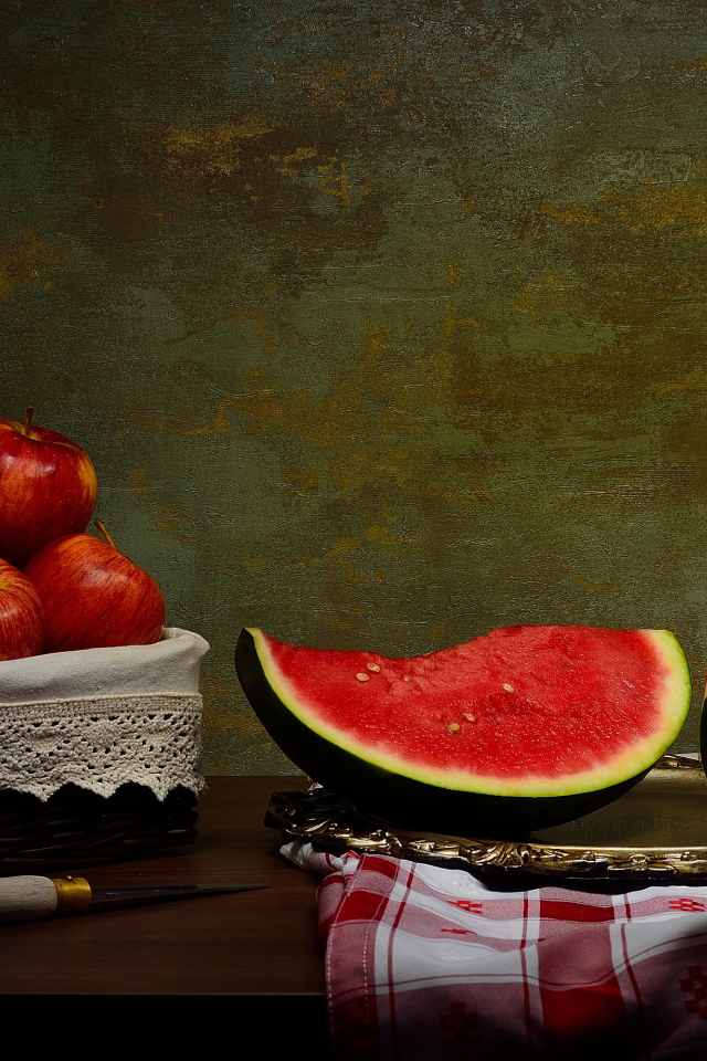 Скибки арбуза на столе с яблоками 