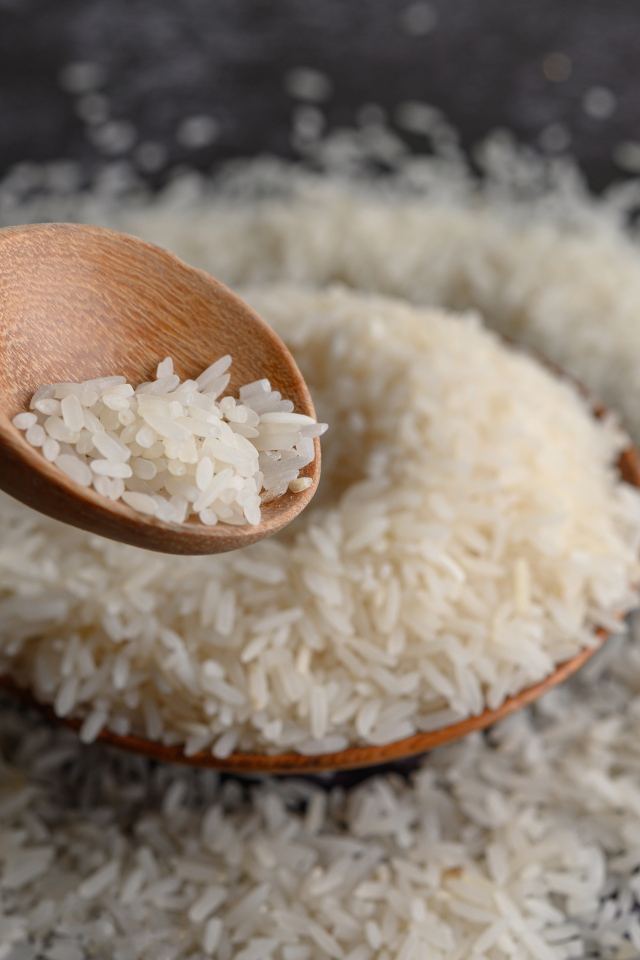 Белый рис на столе с деревянной ложкой 