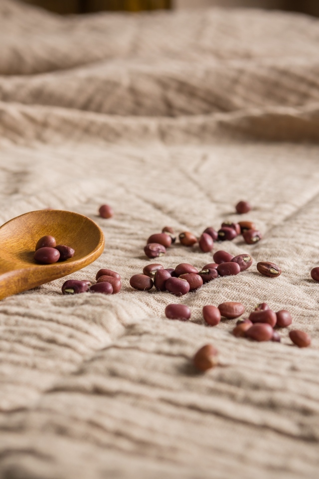 Деревянная ложка на скатерти с фасолью 