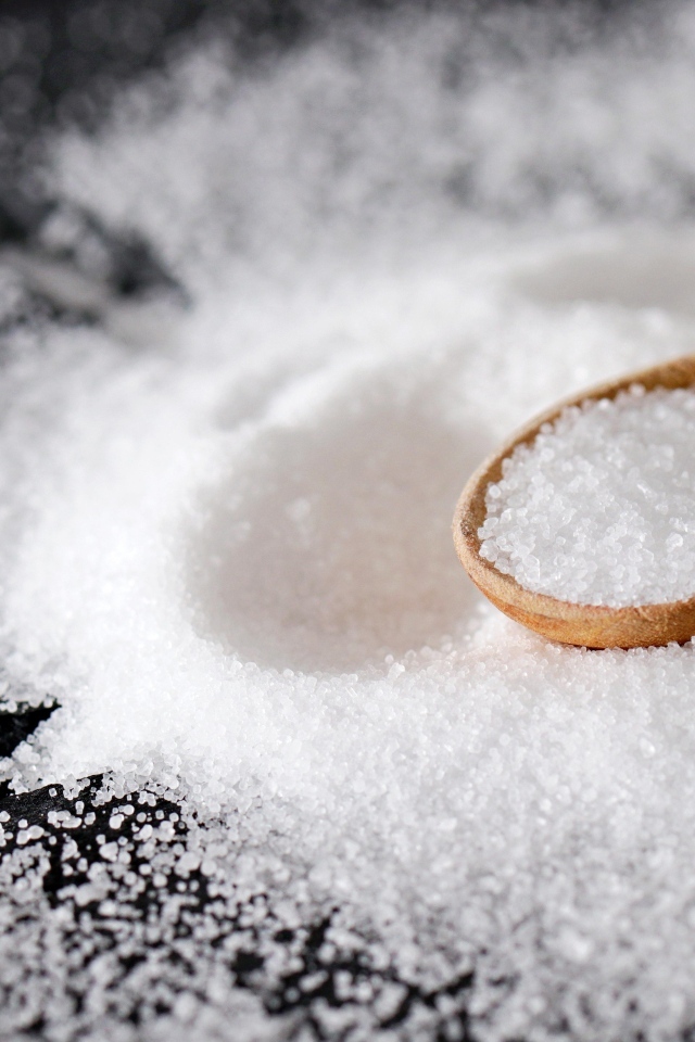 Деревянная ложка с солью на черном столе