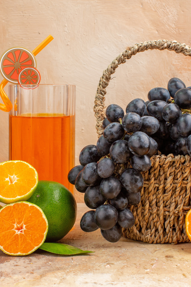 Корзина с виноградом на столе с апельсинами и лаймом