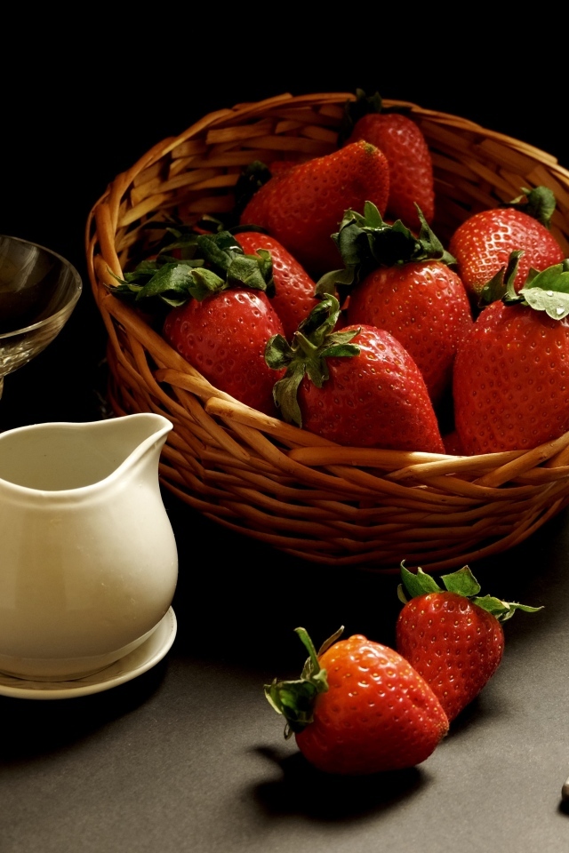 Корзина со спелой красной клубникой на столе с посудой