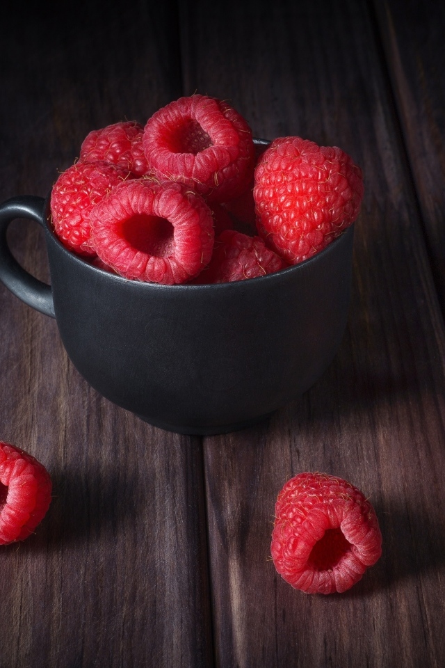 Черная чашка с красными ягодами малины