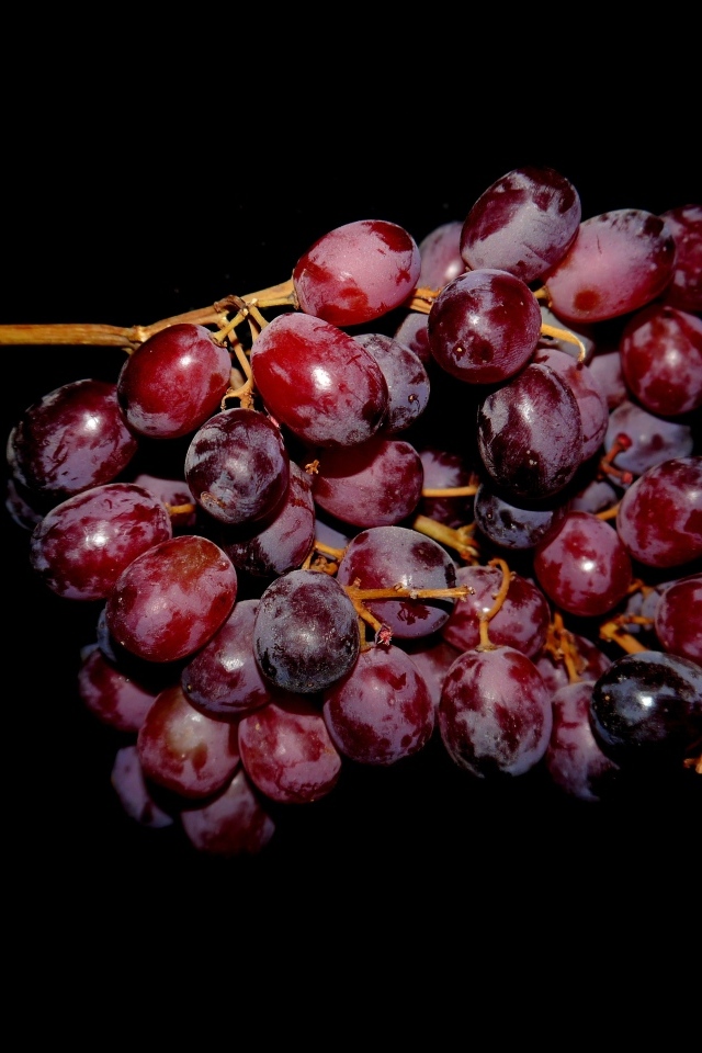 Гроздь розового винограда на черном фоне