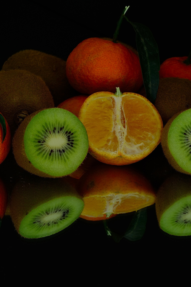 Цитрусовые фрукты на черной зеркальной поверхности