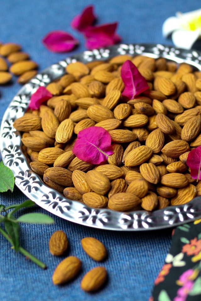 Вкусные миндальные орехи на тарелке с цветами