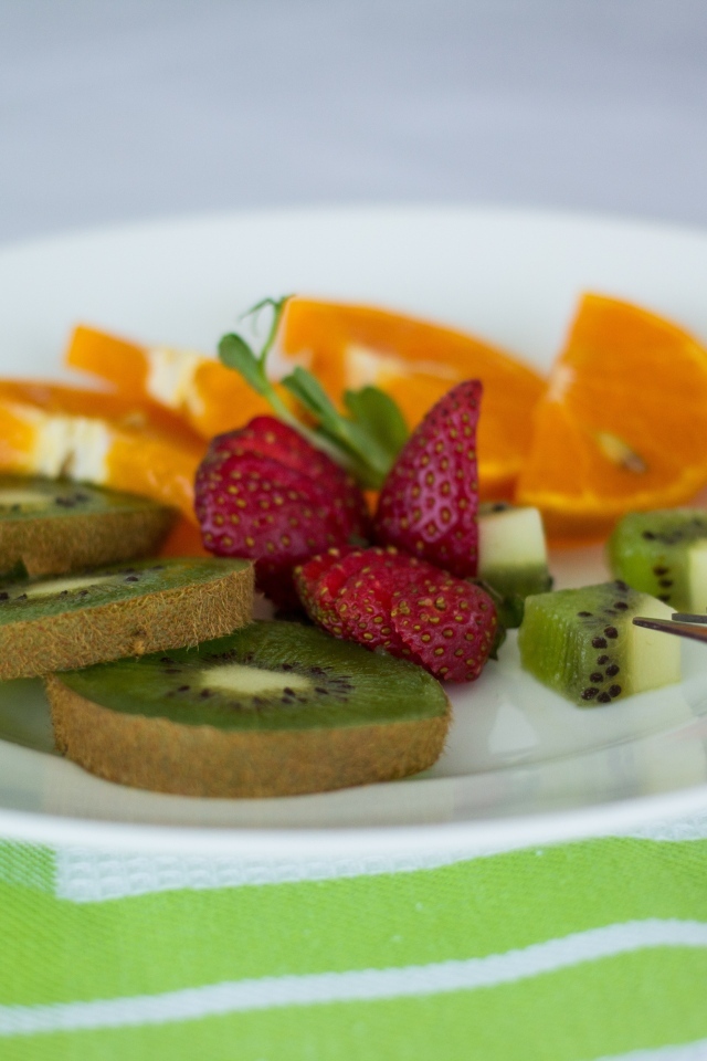 Свежие нарезанные фрукты на тарелке с вилкой