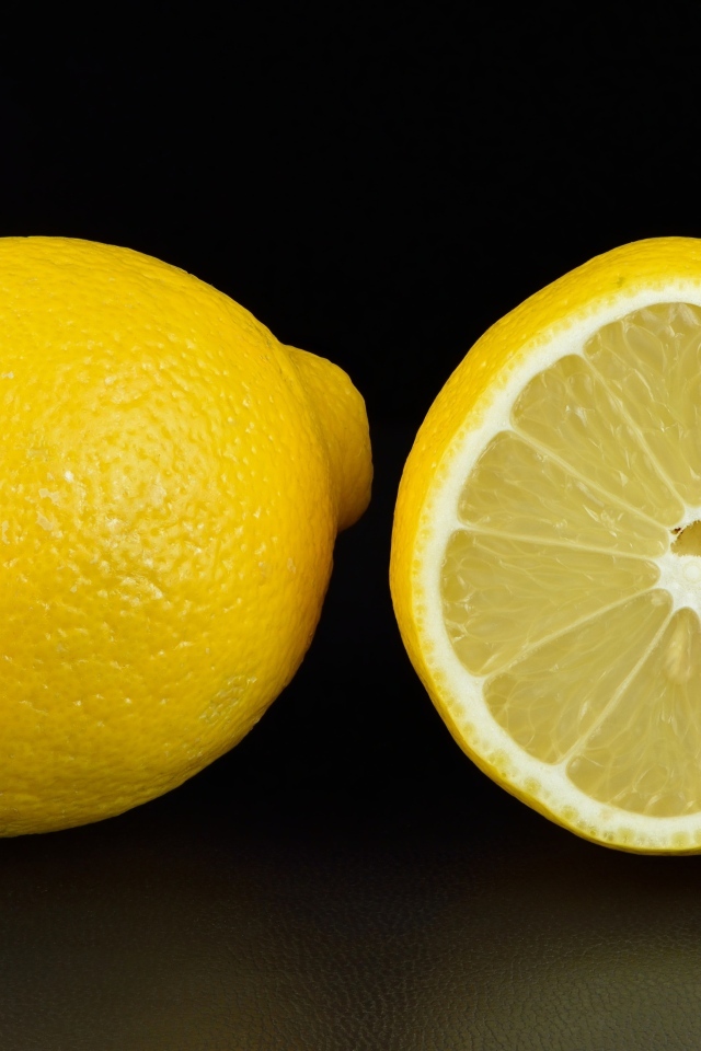 Большой желтый лимон с половиной на черном фоне