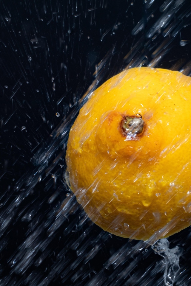 Лимон в брызгах воды на черном фоне