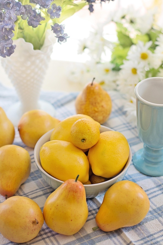 Лимоны и груши на столе с цветами