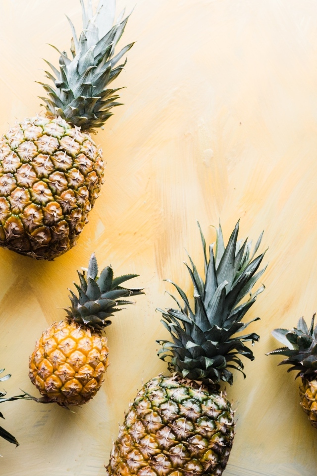 Много ананасов на желтом фоне