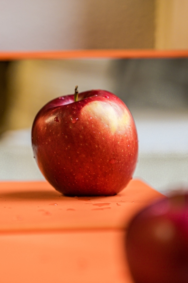 Больше красное яблоко отражается в зеркале 