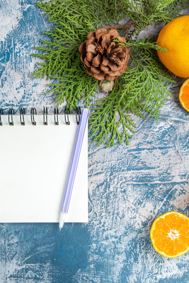 Блокнот на столе с мандаринами и ветками