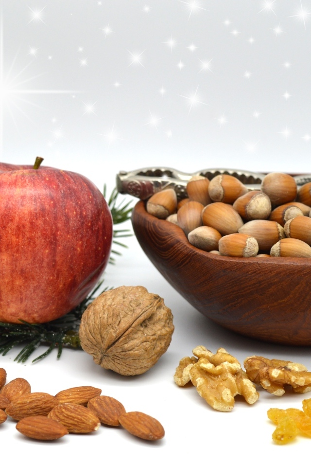 Орехи с яблоком и еловой веткой на столе