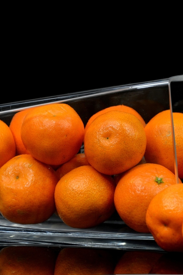 Оранжевые мандарины в стакане на черном фоне