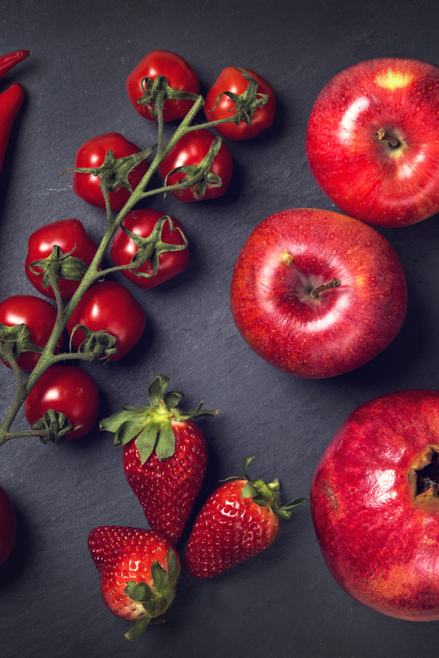 Красные овощи и фрукты на сером столе