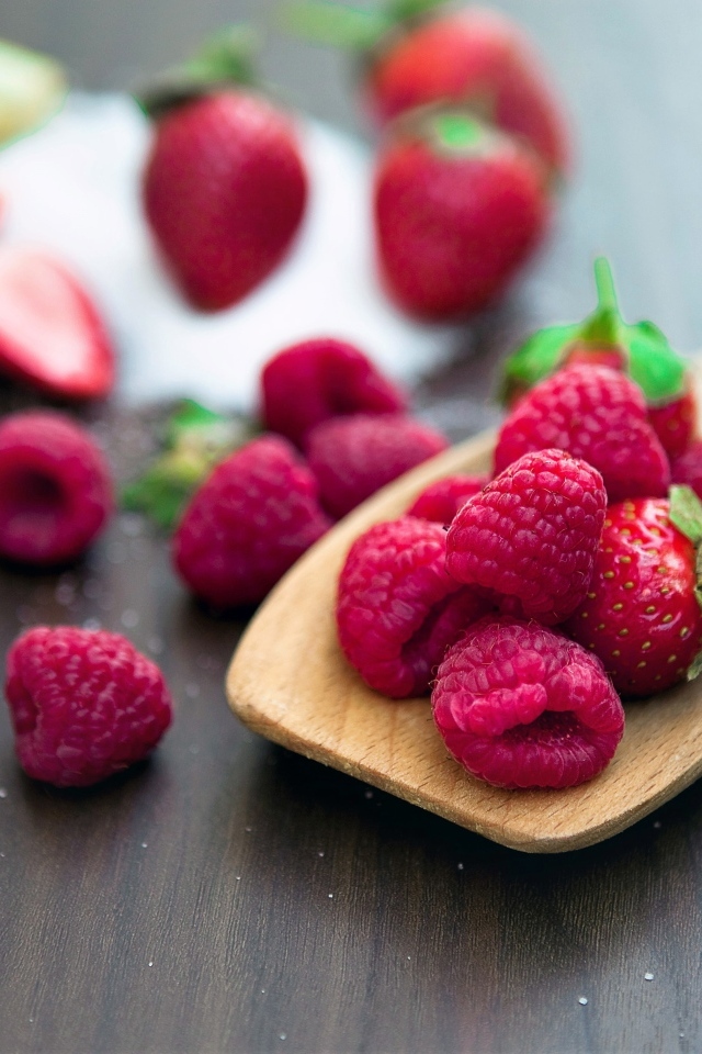 Спелая красная малина с деревянной ложкой на столе