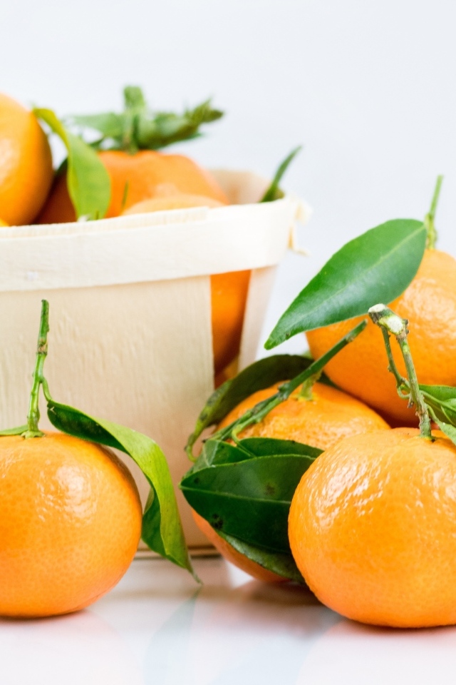 Спелые сладкие мандарины с корзиной на столе