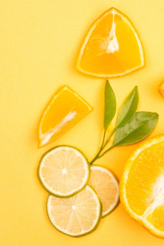 Нарезанные плоды апельсина и лайма на желтом фоне