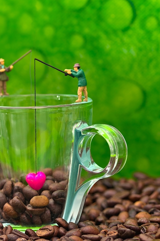 Две фигурки на стеклянной чашкой с кофейными зернами