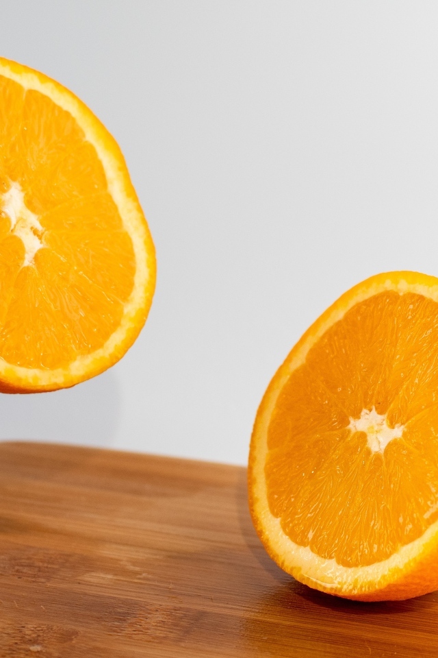 Две половинки апельсина на деревянной доске